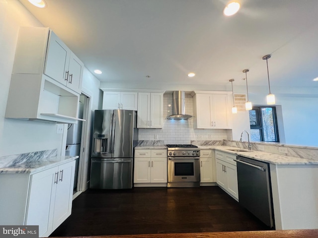 kitchen featuring wall chimney range hood, sink, hanging light fixtures, kitchen peninsula, and stainless steel appliances