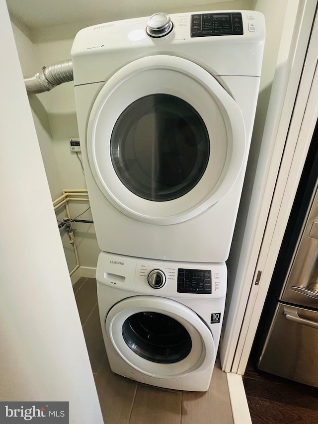 laundry room with dark tile patterned floors and stacked washer and dryer