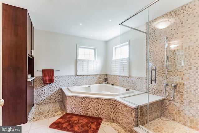 bathroom with separate shower and tub, tile patterned flooring, and tile walls