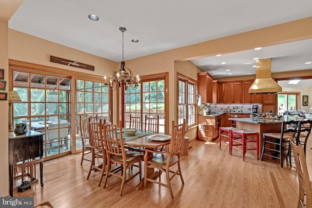 dining room featuring a notable chandelier, a healthy amount of sunlight, and light hardwood / wood-style flooring