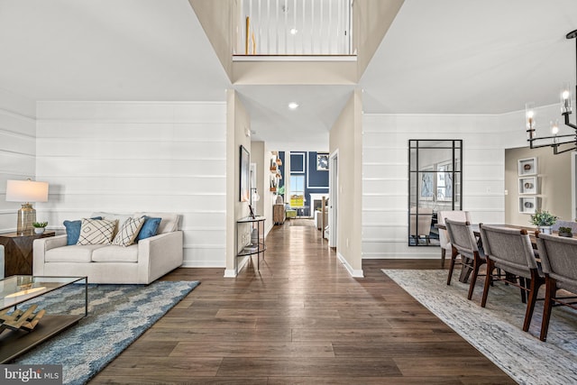 living room with a towering ceiling, dark hardwood / wood-style flooring, and an inviting chandelier