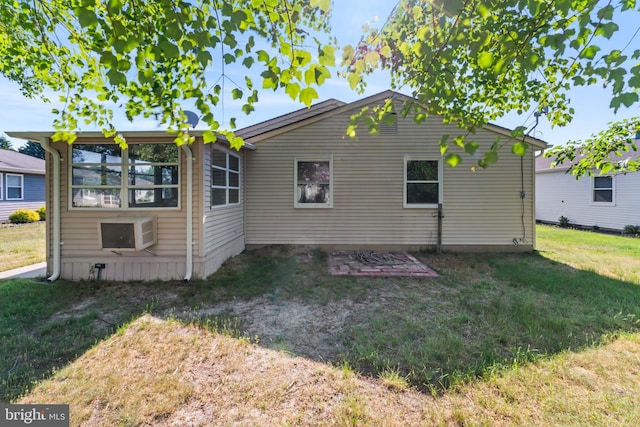 rear view of property with an AC wall unit and a yard