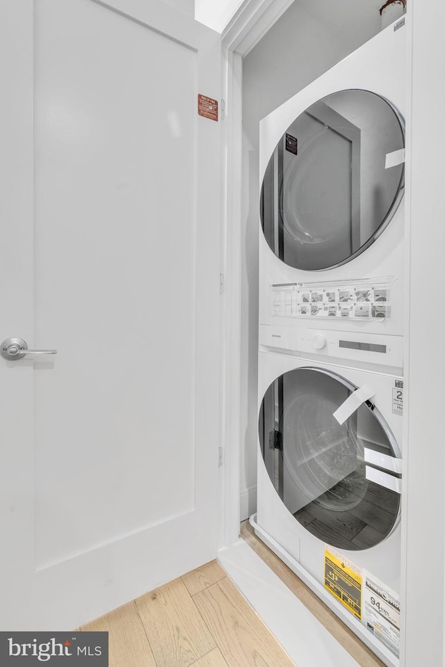 laundry room featuring stacked washing maching and dryer and hardwood / wood-style flooring