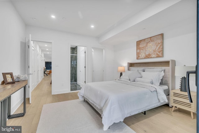 bedroom featuring connected bathroom and light hardwood / wood-style floors