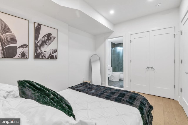 bedroom with connected bathroom and light hardwood / wood-style flooring