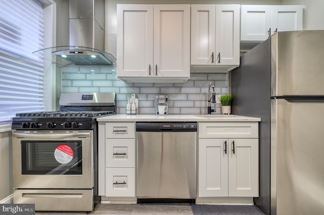 kitchen featuring white cabinetry, wall chimney exhaust hood, and appliances with stainless steel finishes