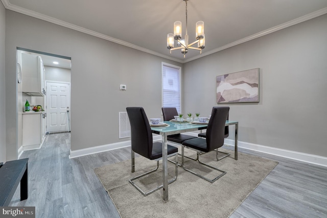 dining room with a chandelier, crown molding, and light hardwood / wood-style flooring