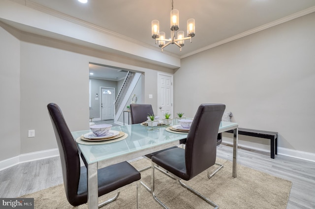 dining area featuring light wood-type flooring, crown molding, and a notable chandelier