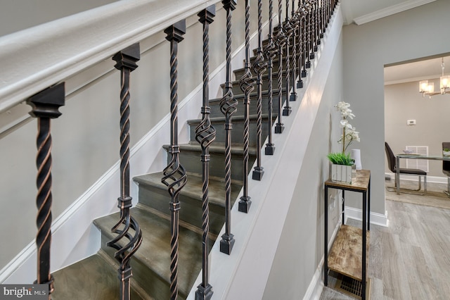 stairs featuring a chandelier, ornamental molding, and hardwood / wood-style flooring