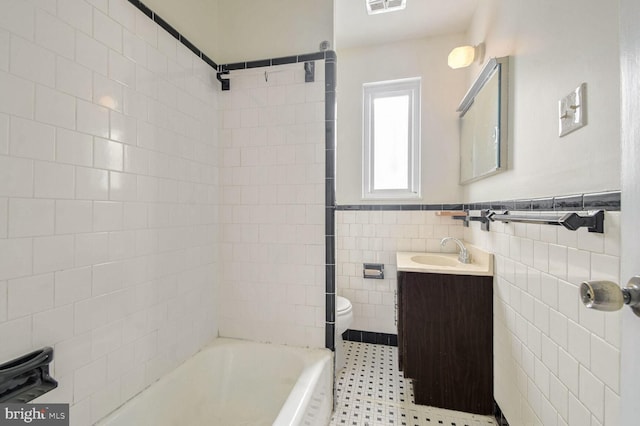 bathroom featuring vanity, toilet, and tile walls