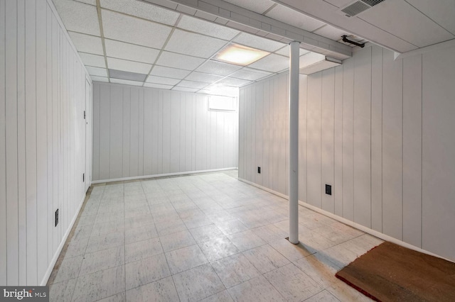 basement with a paneled ceiling and wooden walls