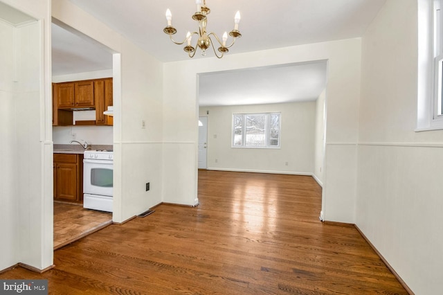 unfurnished dining area featuring dark hardwood / wood-style floors, sink, and a chandelier