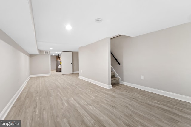 basement with light wood-type flooring and water heater