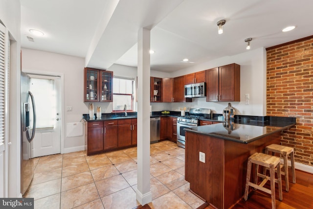 kitchen with sink, a breakfast bar area, stainless steel appliances, light tile patterned flooring, and kitchen peninsula