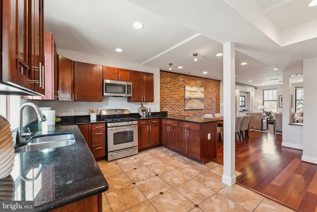 kitchen with light hardwood / wood-style floors, sink, stainless steel appliances, and dark stone counters