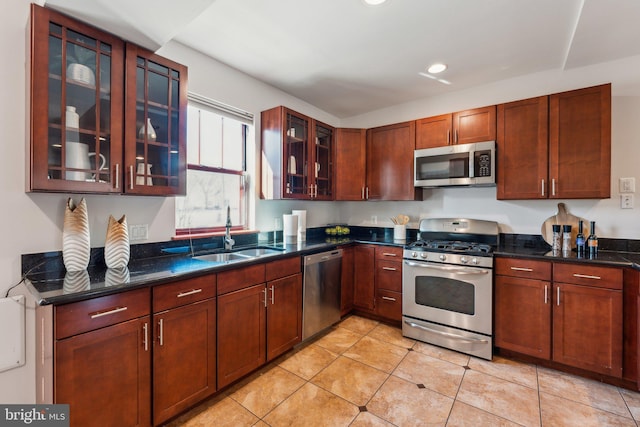 kitchen with light tile patterned flooring, stainless steel appliances, sink, and dark stone counters