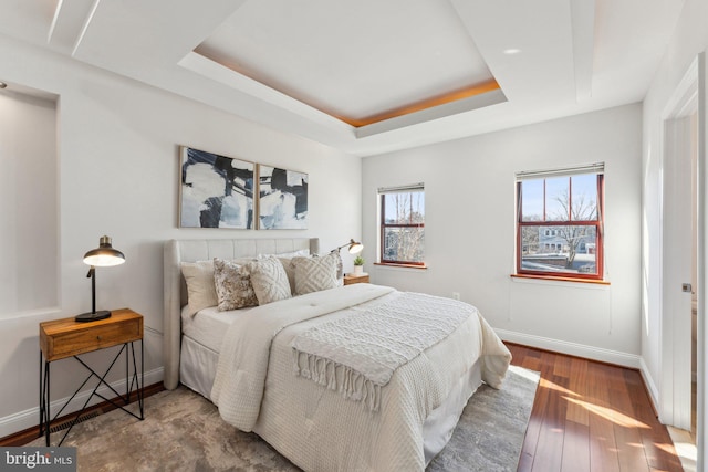 bedroom with a tray ceiling and hardwood / wood-style floors