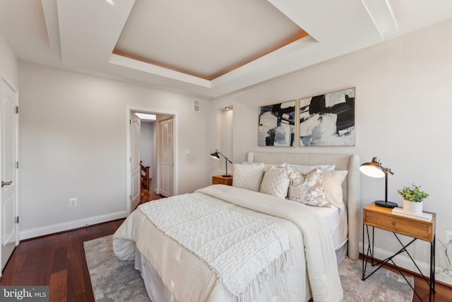 bedroom with dark hardwood / wood-style flooring and a tray ceiling