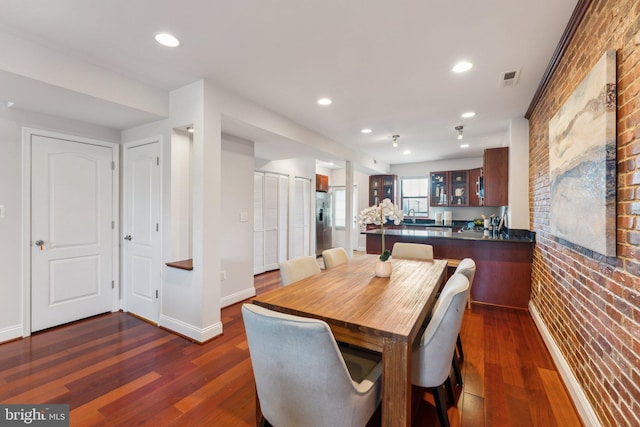 dining room with brick wall, dark wood-type flooring, and sink