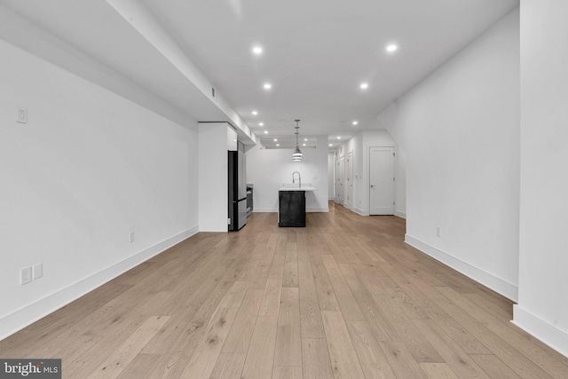 unfurnished living room featuring light wood-type flooring and sink