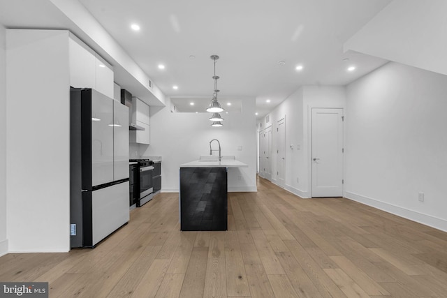 kitchen featuring a center island with sink, white cabinets, stainless steel stove, fridge, and decorative light fixtures