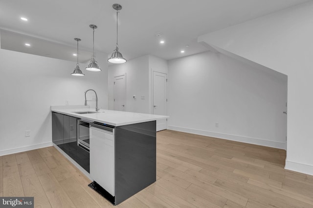 kitchen with kitchen peninsula, sink, light hardwood / wood-style floors, and decorative light fixtures