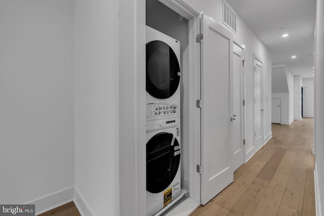 laundry area featuring stacked washer and dryer and light wood-type flooring