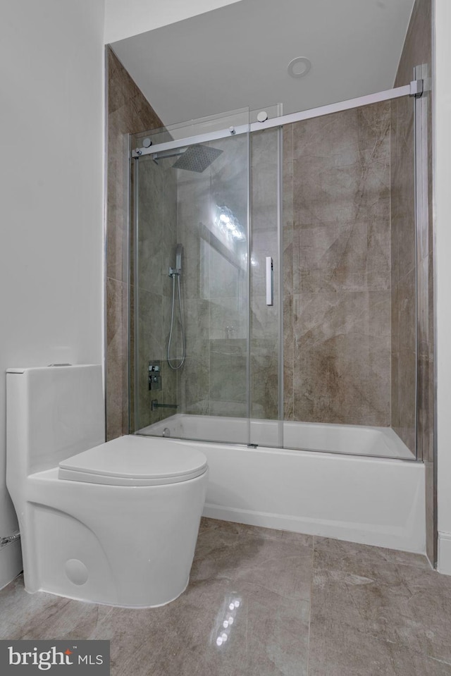 bathroom featuring toilet and combined bath / shower with glass door