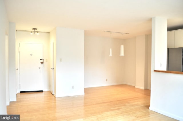 spare room with rail lighting and light hardwood / wood-style floors