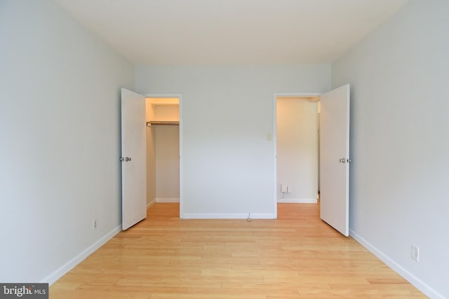 unfurnished bedroom with a walk in closet, light hardwood / wood-style floors, and a closet