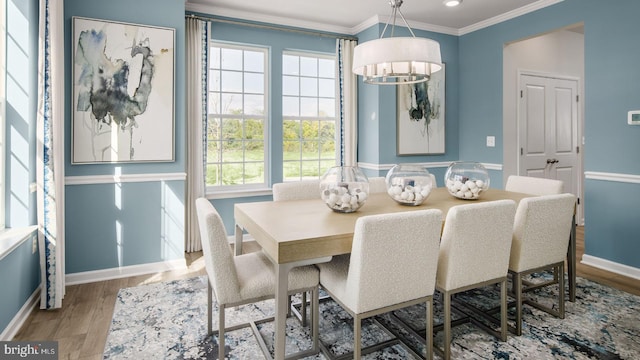 dining room featuring wood-type flooring, crown molding, and a notable chandelier