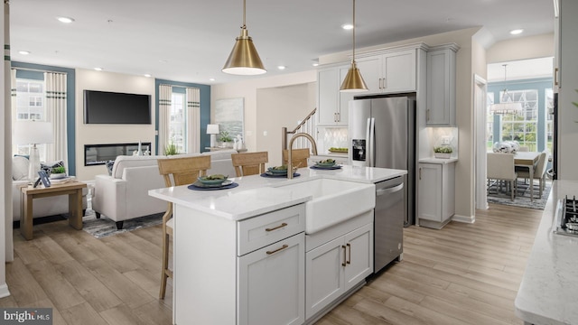 kitchen featuring pendant lighting, light stone counters, sink, and appliances with stainless steel finishes