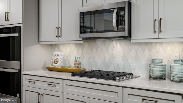 kitchen with appliances with stainless steel finishes, tasteful backsplash, and white cabinetry