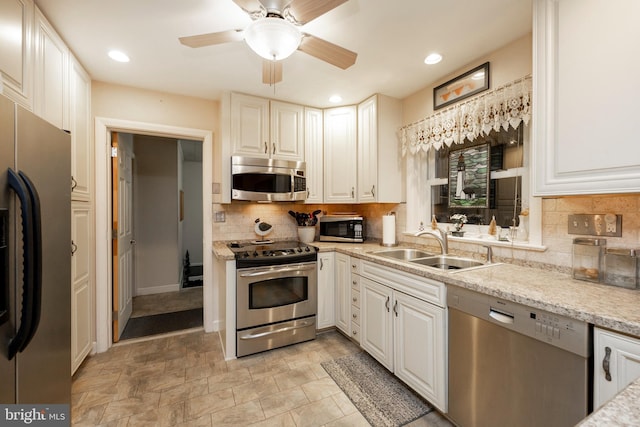 kitchen with light stone countertops, sink, stainless steel appliances, decorative backsplash, and white cabinets