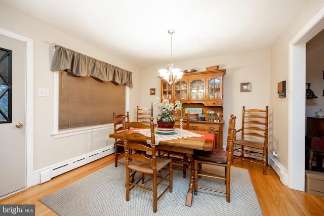 dining space with light wood-type flooring, baseboard heating, and an inviting chandelier