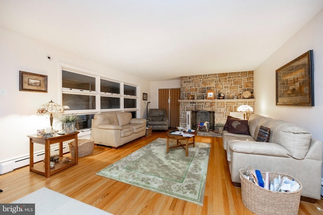 living room featuring baseboard heating, a fireplace, and hardwood / wood-style floors