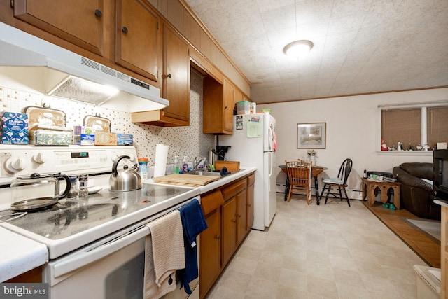 kitchen featuring a textured ceiling, white appliances, baseboard heating, crown molding, and sink