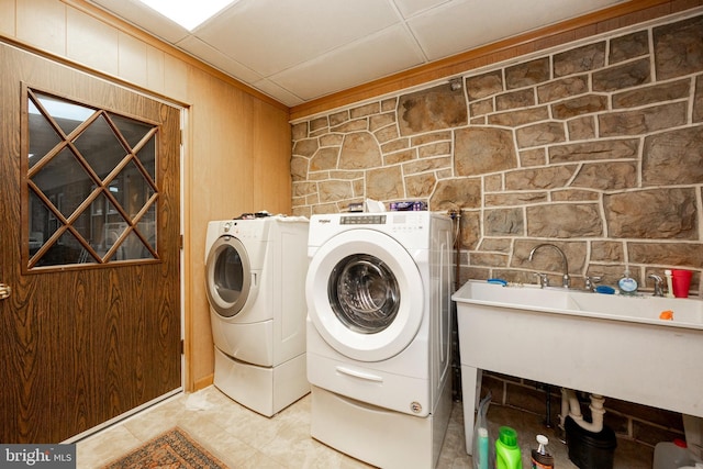 laundry room with independent washer and dryer, wooden walls, and sink