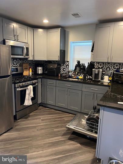 kitchen with gray cabinetry, stainless steel appliances, sink, and hardwood / wood-style flooring