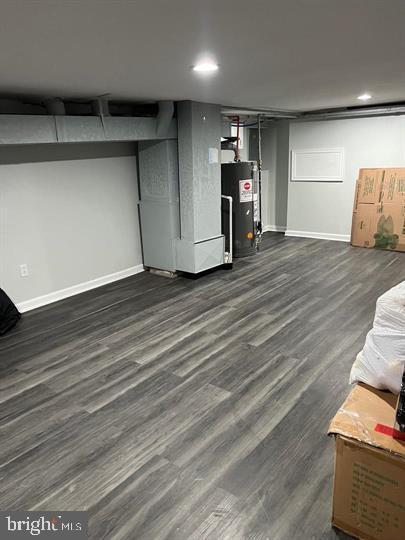 basement with heating unit, water heater, and dark hardwood / wood-style floors