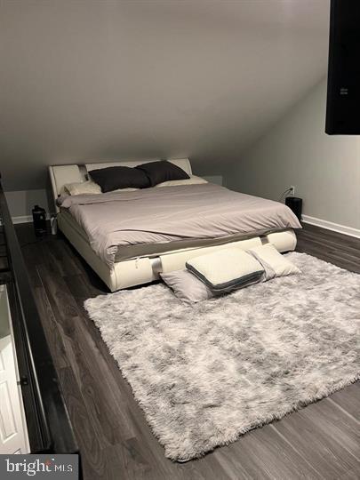 bedroom with dark wood-type flooring and lofted ceiling