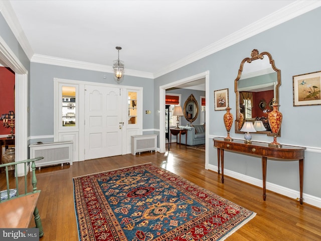 entryway with radiator heating unit, wood-type flooring, and ornamental molding