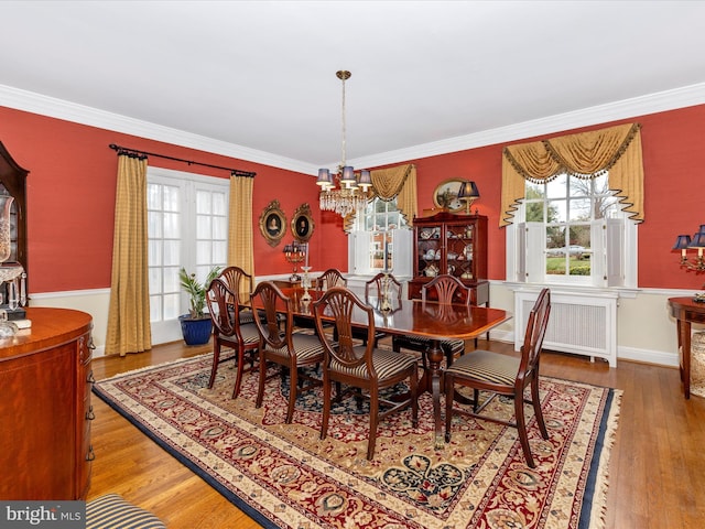 dining room with crown molding, radiator heating unit, a notable chandelier, and hardwood / wood-style flooring