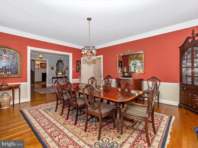 dining room featuring wood-type flooring, ornamental molding, and a notable chandelier