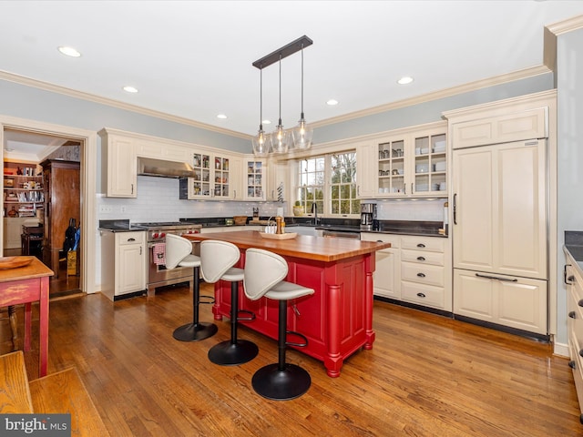 kitchen featuring stainless steel appliances, a center island, hanging light fixtures, butcher block counters, and range hood