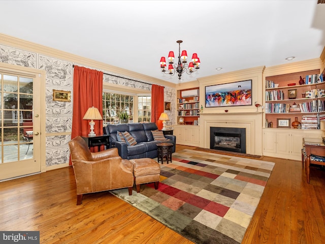 living room with crown molding, built in features, a notable chandelier, and hardwood / wood-style flooring