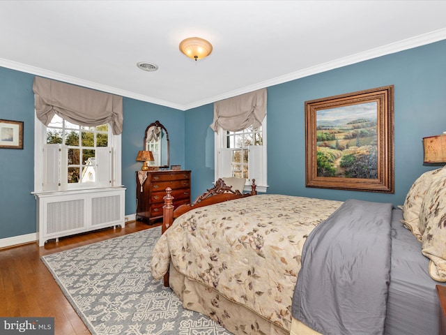 bedroom with dark hardwood / wood-style floors, radiator heating unit, ornamental molding, and multiple windows