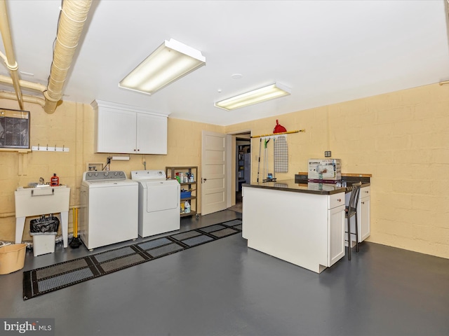 clothes washing area featuring separate washer and dryer, sink, and cabinets