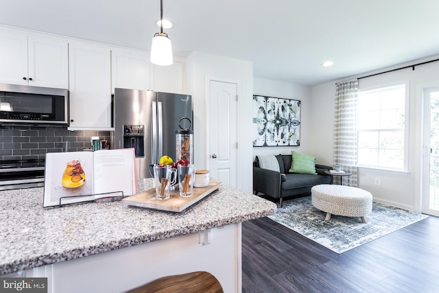 kitchen with light stone countertops, appliances with stainless steel finishes, tasteful backsplash, white cabinetry, and hanging light fixtures