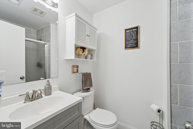 bathroom featuring vanity, a shower with shower door, and toilet